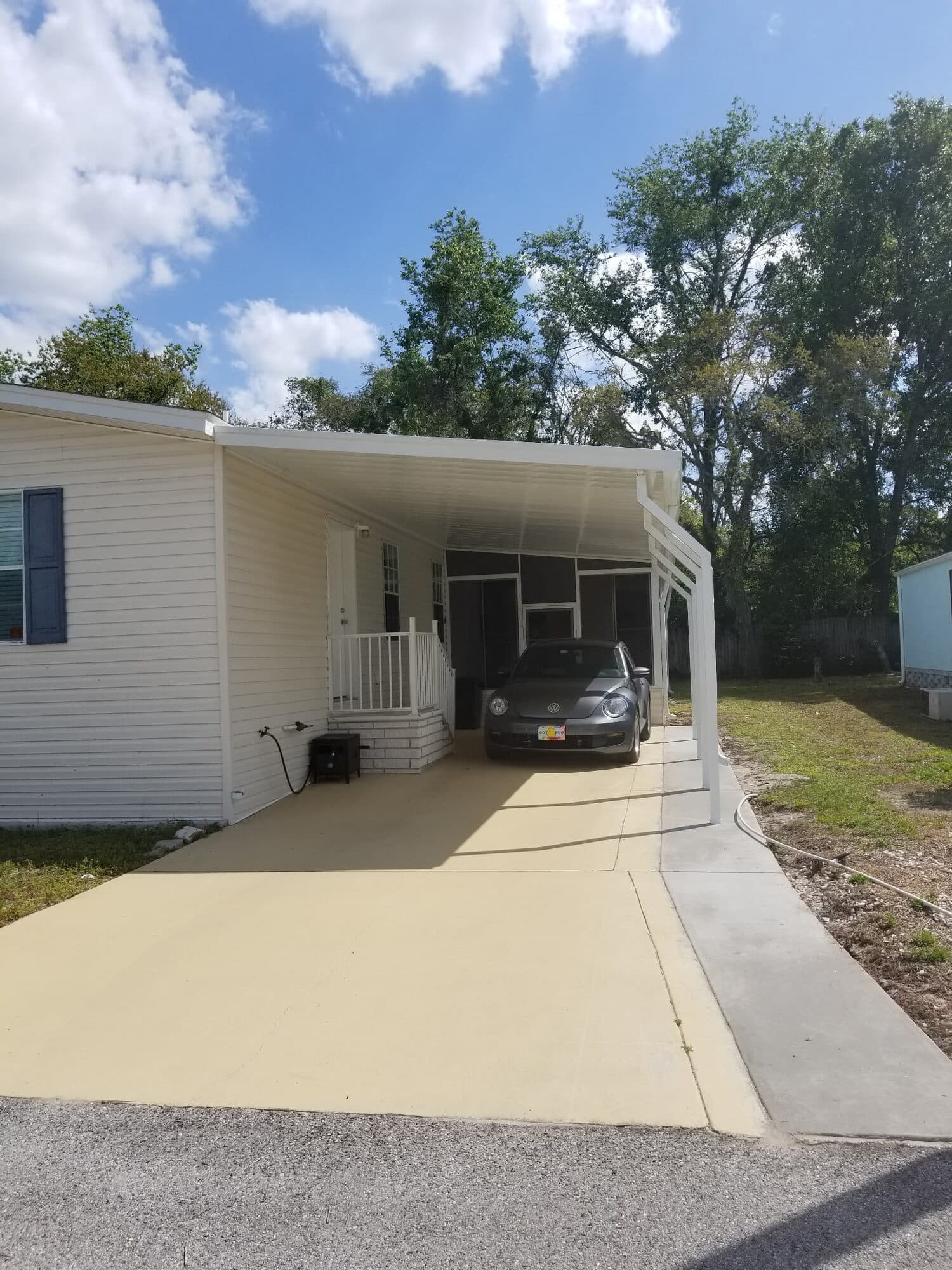 White aluminum carport sheltering a car beside a New Port Richey home